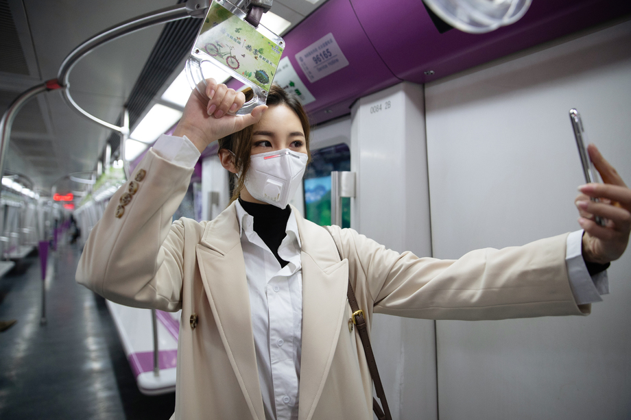戴口罩的年轻女人在地铁里看手机