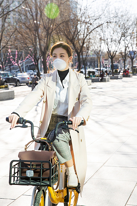 戴口罩的年轻女人骑共享单车图片