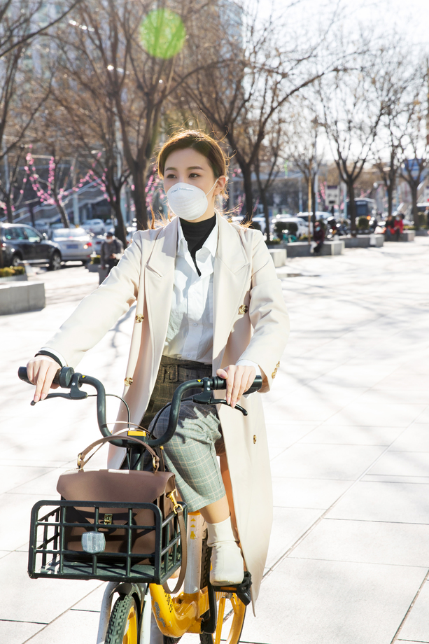 戴口罩的年轻女人骑共享单车图片