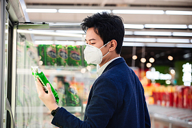 戴口罩的青年男人在超市购物