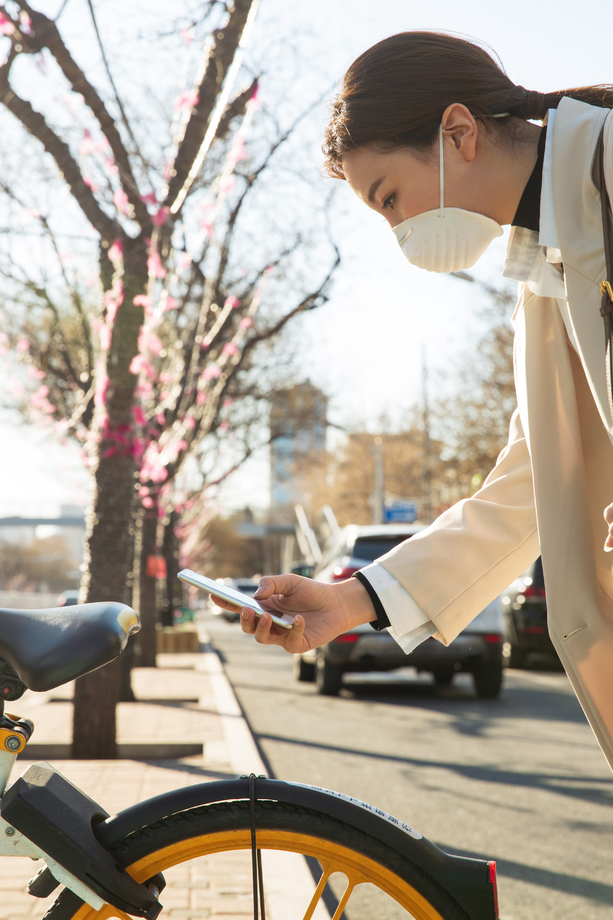 戴口罩的年轻女人扫码骑共享单车 戴口罩的年轻女人扫码骑共享单车