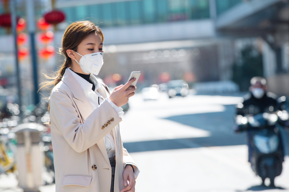 戴口罩的青年女人看手机