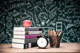 黑板画前的桌子上的书和文具