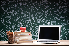 黑板画前的桌子上的书和笔记本电脑