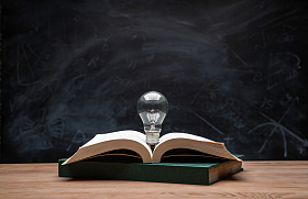 黑板前桌子上的书和灯泡