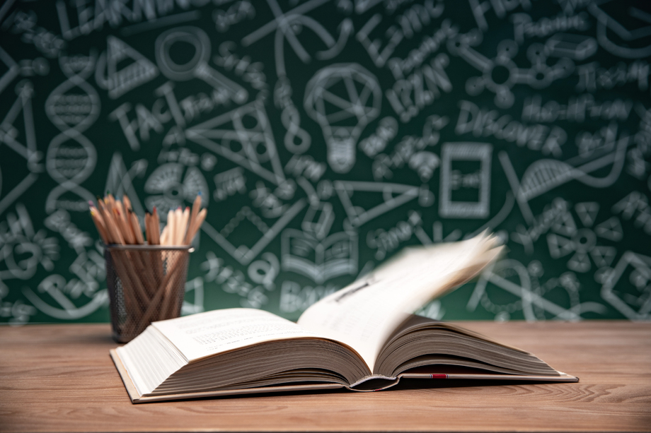 黑板画前的桌子上摊开的书和笔筒 黑板画前的桌子上摊开的书和笔筒