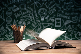 黑板画前的桌子上打开的书和笔筒