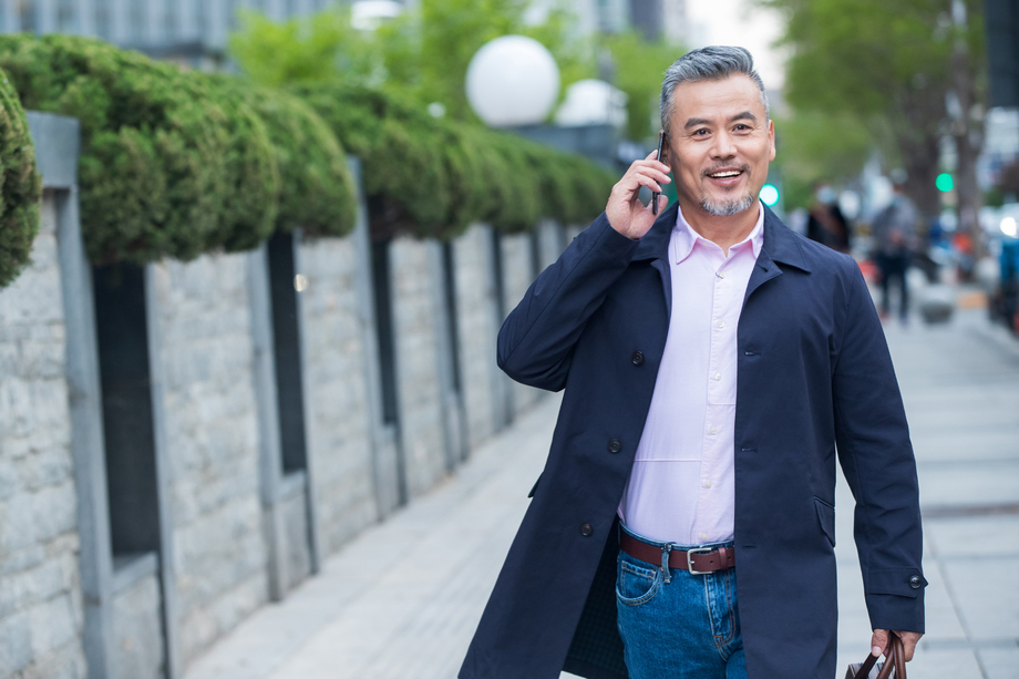 户外拎着公文包打电话的商务中老年男子 户外拎着公文包打电话的商务中老年男子