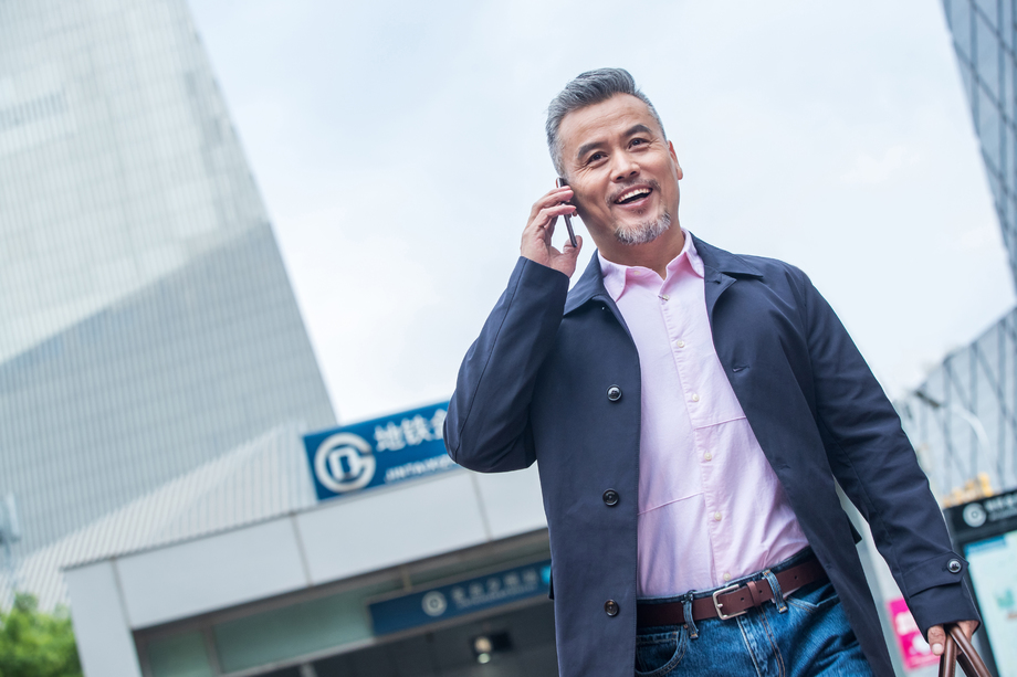 地铁站外拎着公文包打电话的商务中老年男子 地铁站外拎着公文包打电话的商务中老年男子