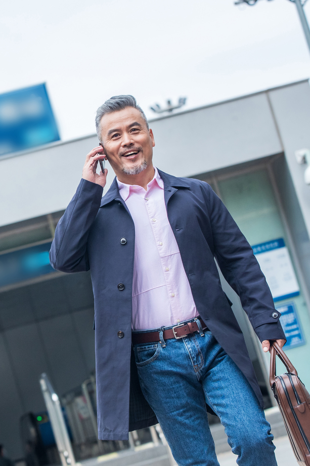 地铁站外拎着公文包打电话的商务中老年男子 地铁站外拎着公文包打电话的商务中老年男子