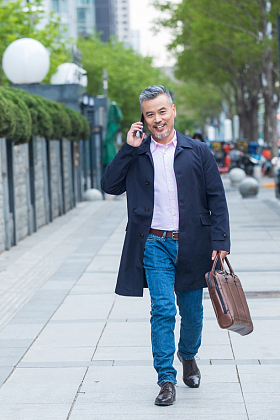 户外拎着公文包打电话的商务中老年男子