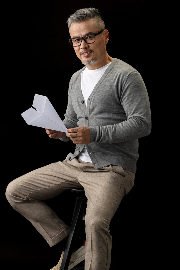 坐在椅子上的中老年男士拿着纸飞机