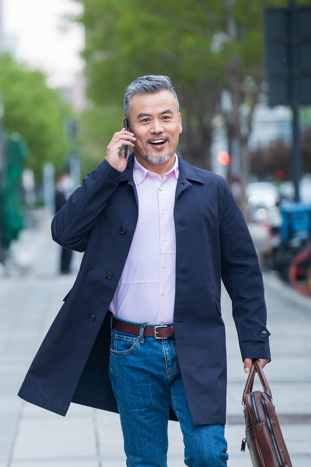 户外拎着公文包打电话的商务中老年男子 户外拎着公文包打电话的商务中老年男子