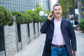 户外拎着公文包打电话的商务中老年男子