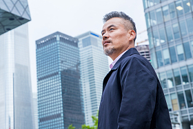 中老年商务男士站着楼群中间图片