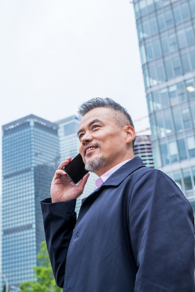 商务男士站着楼群中间打电话图片