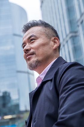 中老年商务男士站着楼群中间图片