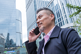 商务男士站着楼群中间打电话