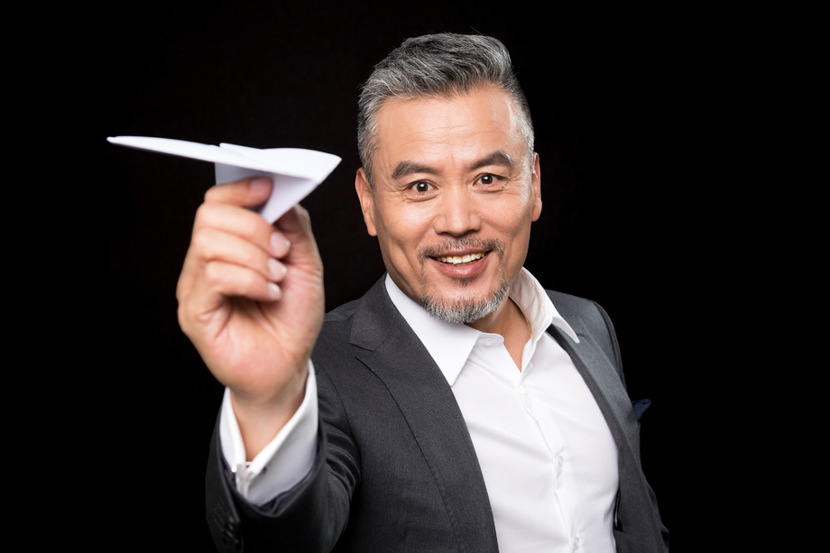 快乐的中老年商务男士拿着纸飞机 快乐的中老年商务男士拿着纸飞机