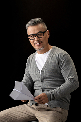 坐在椅子上的中老年男士拿着纸飞机