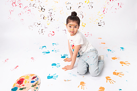 手上涂满颜料画画的小女孩