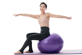 中年女性坐在瑜伽球上练习瑜伽