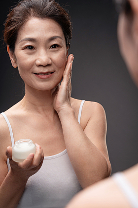 对着镜子涂抹护肤品的中年女人