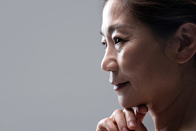 手托下巴思考的中年女性照片