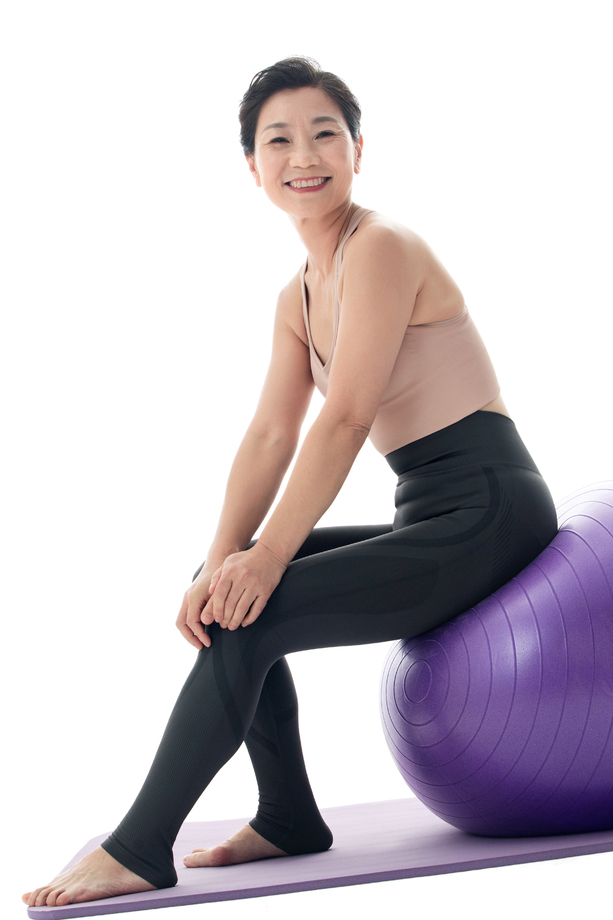 中年女性坐在瑜伽球上 中年女性坐在瑜伽球上