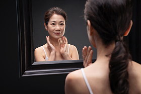 照镜子按摩颈部的中年女人
