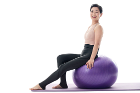 快乐的中年女性坐在瑜伽球上图片