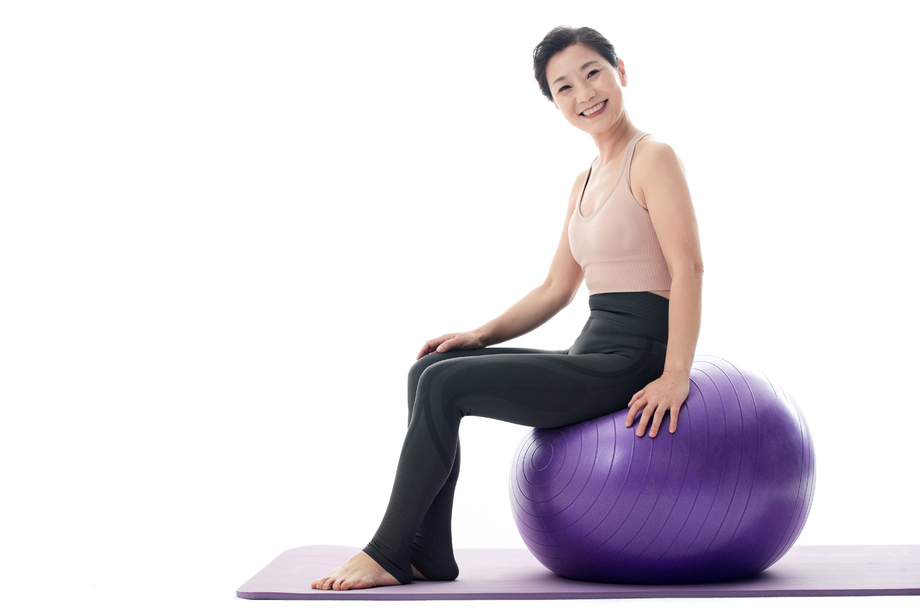 快乐的中年女性坐在瑜伽球上 快乐的中年女性坐在瑜伽球上