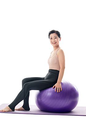 快乐的中年女性坐在瑜伽球上照片