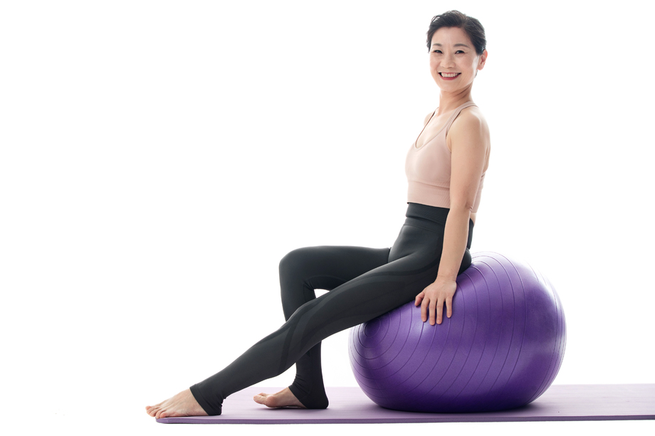 快乐的中年女性坐在瑜伽球上图片