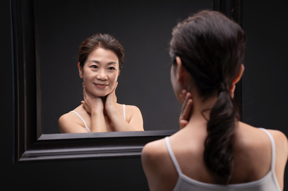 优雅的中年女人对着镜子做颈部护理
