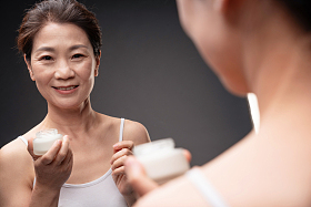 镜子里反射的涂抹护肤品的优雅女人