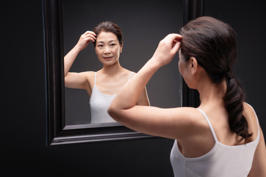 中年女性欣赏镜子中的自己 中年女性欣赏镜子中的自己