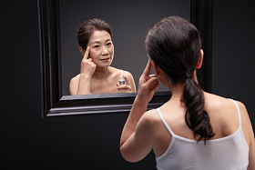 优雅的中年女人对着镜子涂抹爽肤水