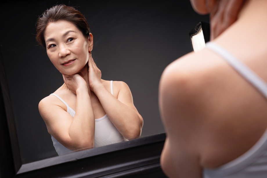 优雅的中年女人对着镜子做颈部护理