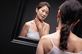 中老年女人对着镜子做颈部护理
