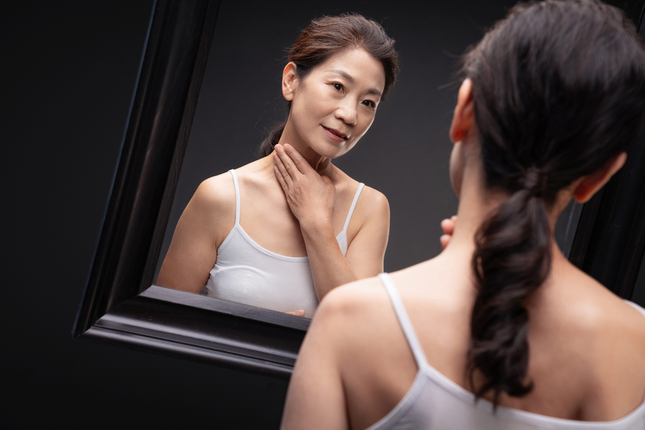 中老年女人对着镜子做颈部护理