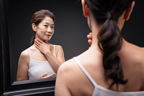 中老年女人对着镜子做颈部护理