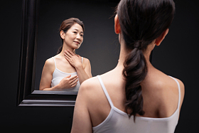 中老年女人对着镜子做颈部护理