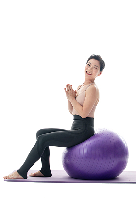 快乐的中年女性坐在瑜伽球上照片