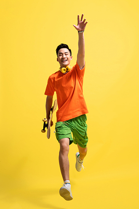 拿着滑板跳跃的青年男人图片