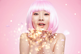 带着假发的年轻女孩吹撒手中的亮片