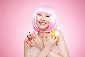 手指夹着马卡龙的年轻女孩图片