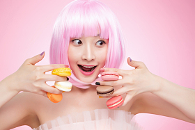 手指夹着马卡龙的年轻女孩图片