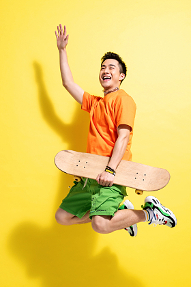 拿着滑板跳跃的青年男人