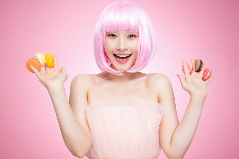 手指夹着马卡龙的快乐年轻女孩
